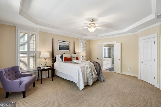 bedroom featuring connected bathroom, crown molding, a tray ceiling, ceiling fan, and light colored carpet