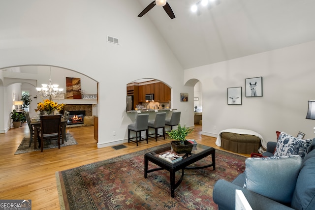 living room featuring ceiling fan with notable chandelier, high vaulted ceiling, and hardwood / wood-style flooring