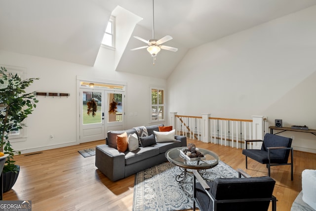 living room with light hardwood / wood-style floors, lofted ceiling with skylight, and ceiling fan