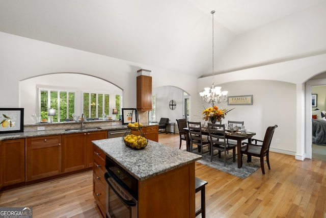 kitchen with light hardwood / wood-style floors, sink, vaulted ceiling, hanging light fixtures, and a kitchen island