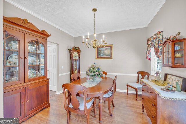 dining area with a textured ceiling, light hardwood / wood-style flooring, a notable chandelier, and crown molding