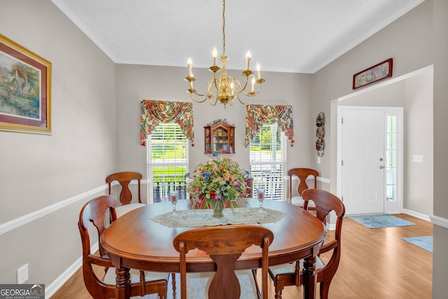 dining space with ornamental molding, a textured ceiling, a chandelier, and light hardwood / wood-style floors