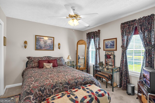 carpeted bedroom featuring ceiling fan and a textured ceiling