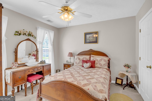 bedroom featuring ceiling fan, light carpet, and a textured ceiling