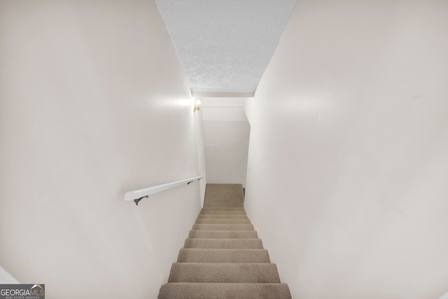 stairs featuring a textured ceiling