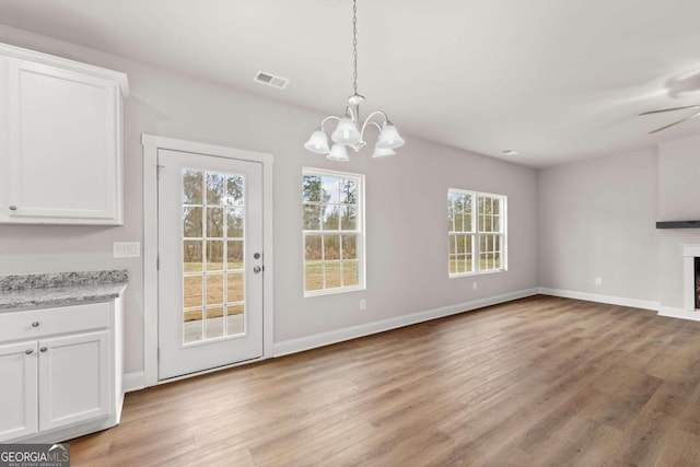 32 Joseph Ln, Hartwell, GA 30643 - unfurnished dining area featuring light wood-type flooring, a chandelier, a fireplace, and ceiling fan