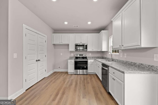 32 Joseph Ln, Hartwell, GA 30643 - kitchen featuring stainless steel appliances, white cabinets, light wood-style flooring, recessed lighting, and light stone countertops