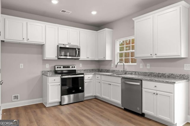 32 Joseph Ln, Hartwell, GA 30643 - kitchen with appliances with stainless steel finishes, white cabinetry, recessed lighting, light wood finished floors, and light stone counters