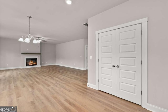 32 Joseph Ln, Hartwell, GA 30643 - unfurnished living room featuring a chandelier, light wood-type flooring, and a warm lit fireplace