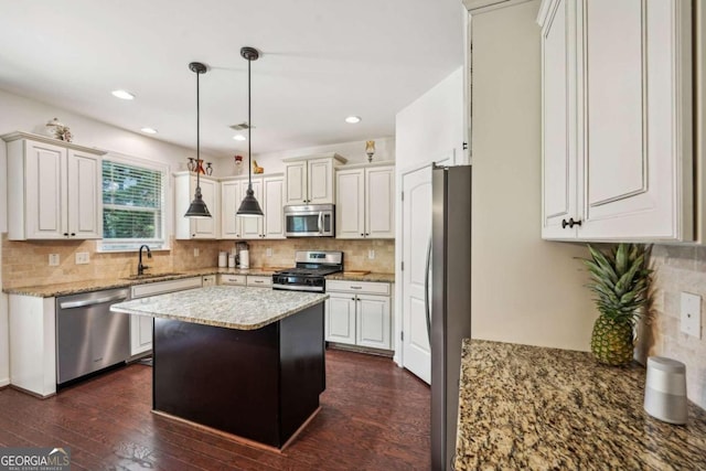 kitchen featuring light stone counters, sink, dark wood-type flooring, a kitchen island, and appliances with stainless steel finishes