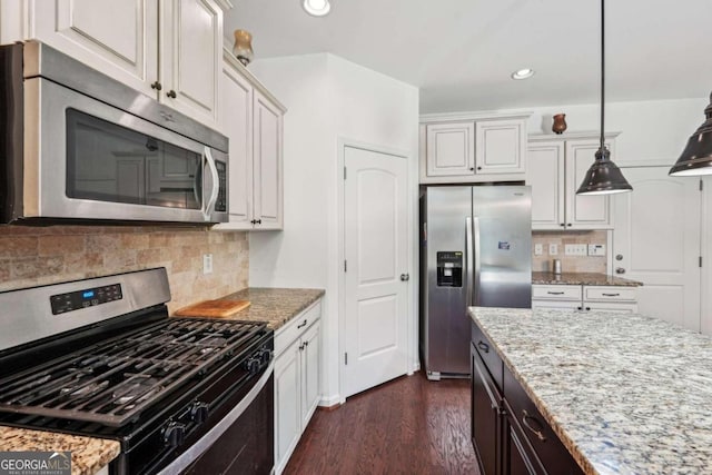 kitchen with white cabinets, backsplash, appliances with stainless steel finishes, light stone counters, and dark wood-type flooring