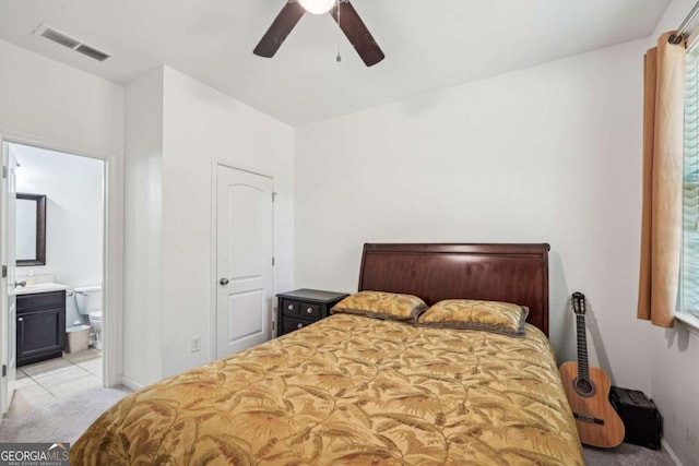 bedroom with ceiling fan, light carpet, and ensuite bath