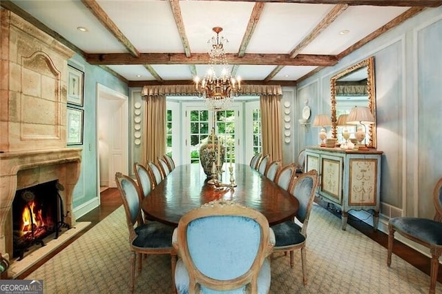 dining area featuring hardwood / wood-style floors, a high end fireplace, beamed ceiling, and an inviting chandelier