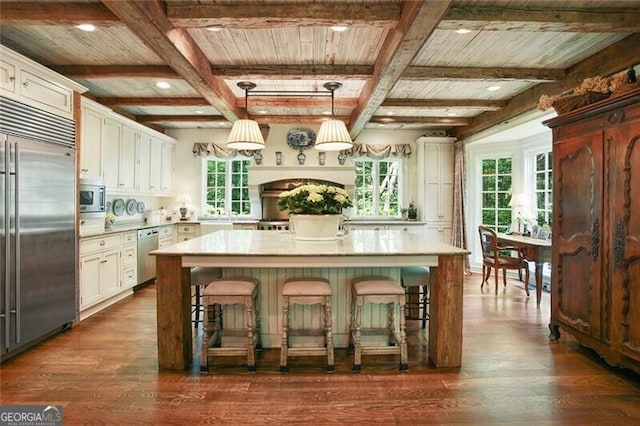 kitchen featuring a kitchen island, built in appliances, a kitchen breakfast bar, dark wood-type flooring, and white cabinets