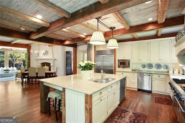 kitchen featuring an island with sink, built in appliances, dark hardwood / wood-style floors, and light stone countertops