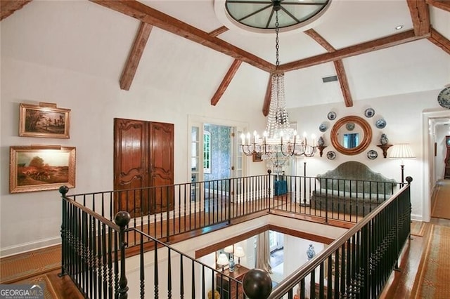 hallway with an inviting chandelier, wood-type flooring, and lofted ceiling with beams