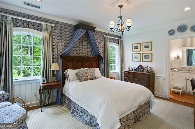 bedroom with crown molding, a chandelier, and connected bathroom