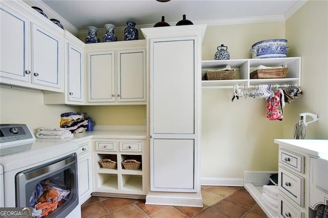 clothes washing area featuring crown molding, cabinets, washer and clothes dryer, and tile patterned flooring