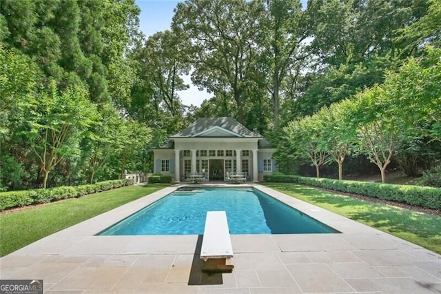 view of swimming pool featuring a yard, a diving board, and a patio area