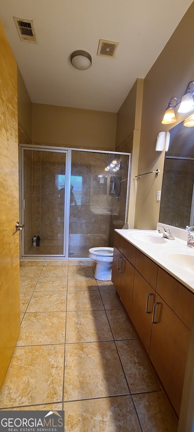 bathroom with tile patterned flooring, walk in shower, toilet, and vanity