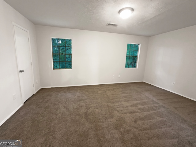 unfurnished room with dark carpet and a textured ceiling