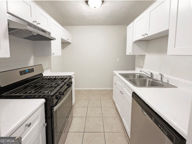 kitchen featuring a textured ceiling, light tile patterned floors, stainless steel appliances, sink, and white cabinetry