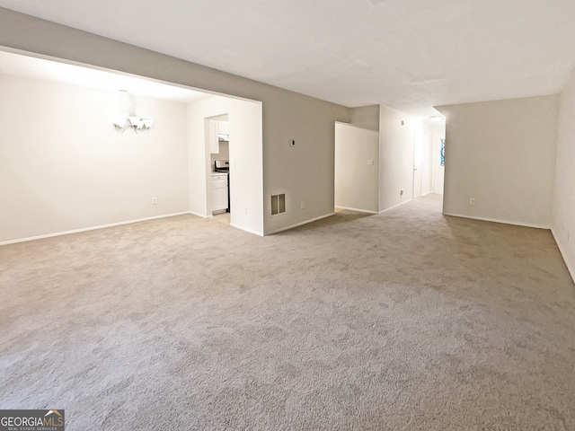 carpeted spare room featuring an inviting chandelier