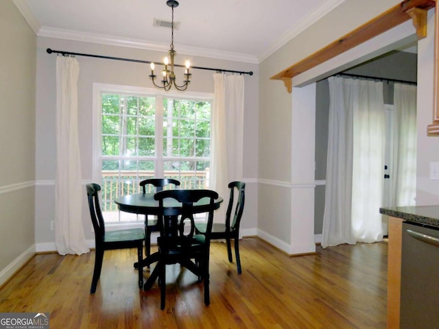 dining space with wood-type flooring, ornamental molding, and a notable chandelier