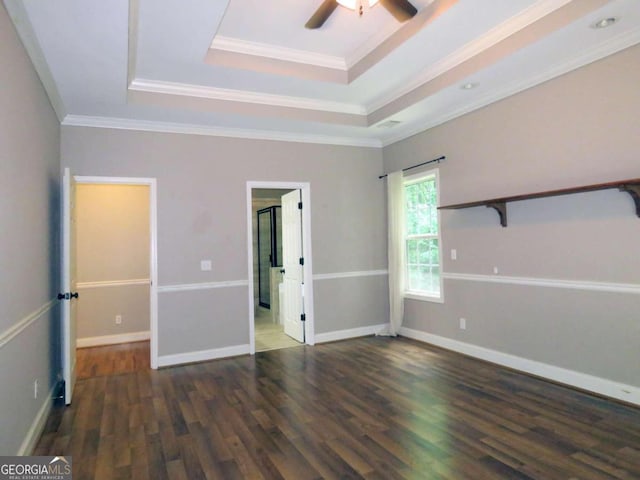 unfurnished room with ceiling fan, a tray ceiling, dark hardwood / wood-style flooring, and crown molding