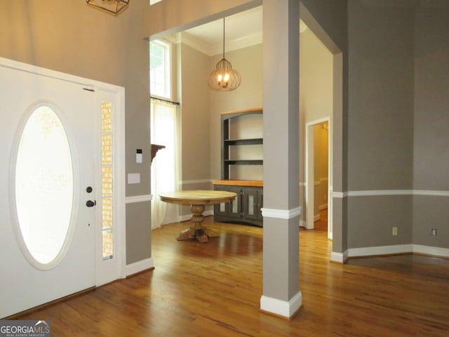 entrance foyer featuring hardwood / wood-style flooring, ornamental molding, a healthy amount of sunlight, and an inviting chandelier