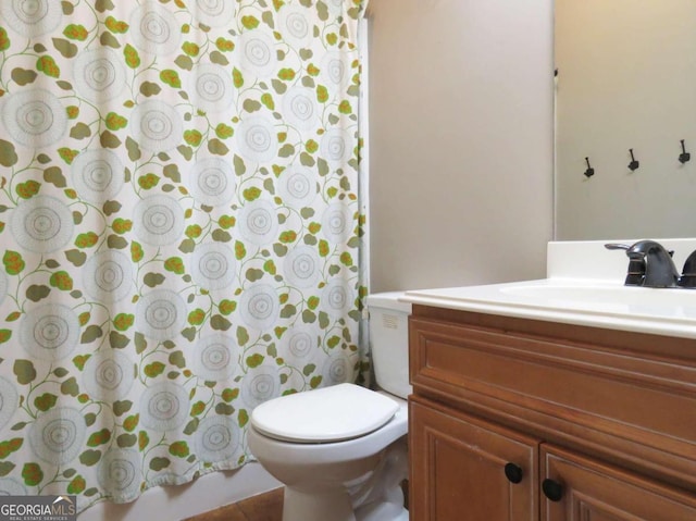 bathroom featuring toilet, vanity, and a shower with curtain