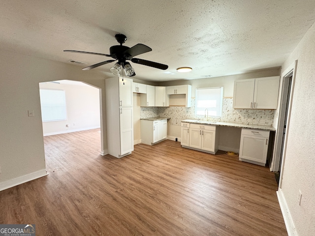 kitchen featuring hardwood / wood-style floors, a textured ceiling, backsplash, sink, and ceiling fan