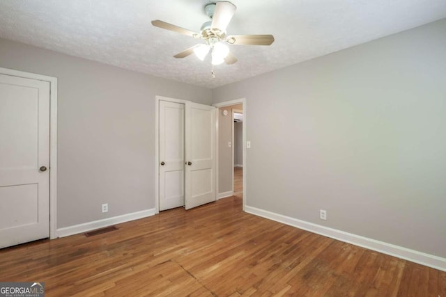 unfurnished bedroom featuring ceiling fan, light hardwood / wood-style floors, and a textured ceiling