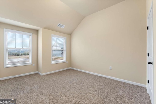 unfurnished room featuring light colored carpet, a wealth of natural light, visible vents, and vaulted ceiling