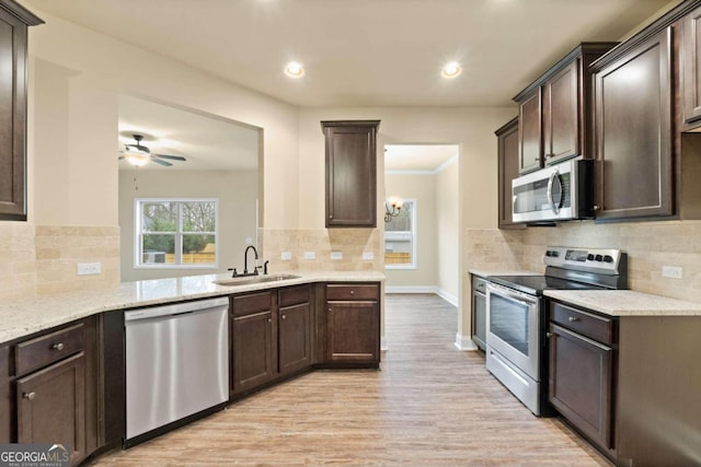 kitchen featuring a peninsula, appliances with stainless steel finishes, a sink, and dark brown cabinetry