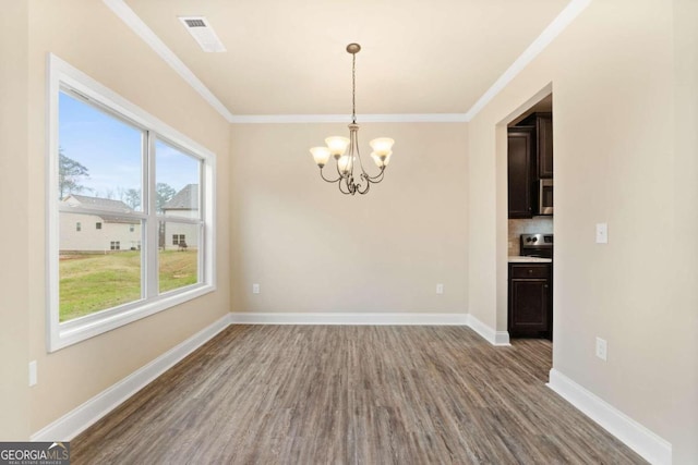 unfurnished dining area with ornamental molding, a chandelier, baseboards, and wood finished floors