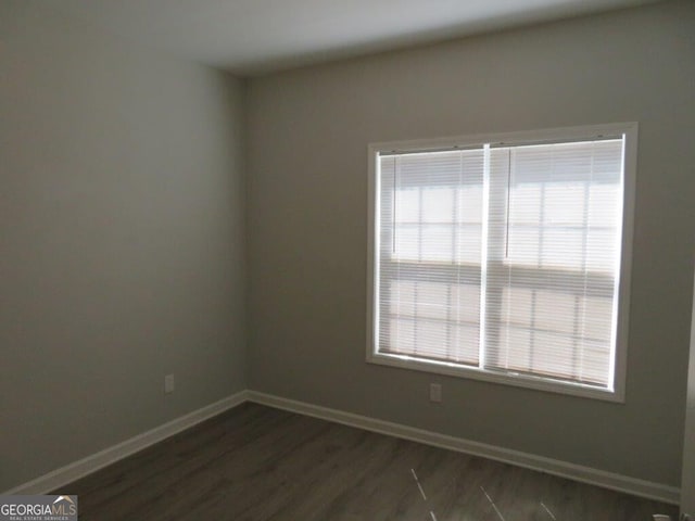 unfurnished room featuring baseboards and dark wood-type flooring