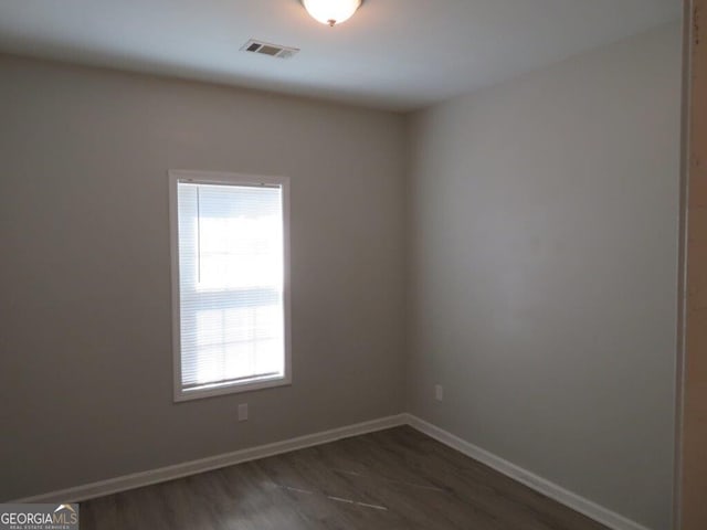 unfurnished room featuring wood finished floors, baseboards, and visible vents