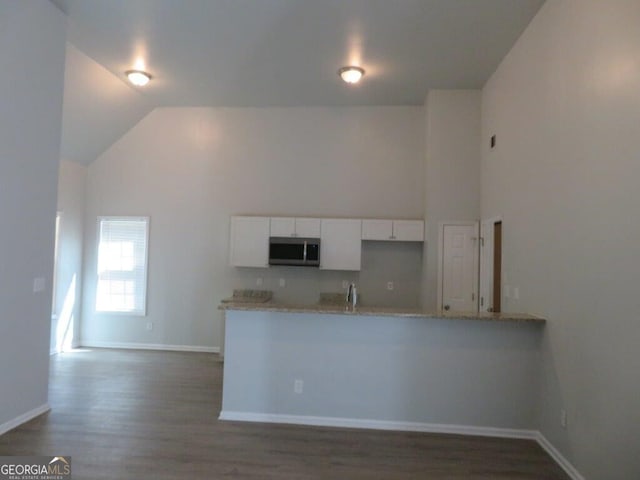 kitchen with white cabinetry, stainless steel microwave, baseboards, and dark wood-type flooring