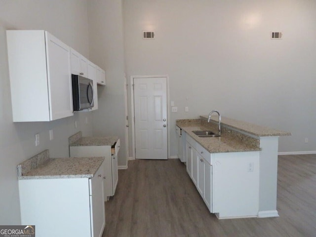 kitchen with a sink, stainless steel microwave, a peninsula, and visible vents