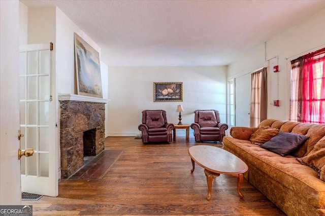 living room featuring a fireplace, dark wood-type flooring, and a textured ceiling