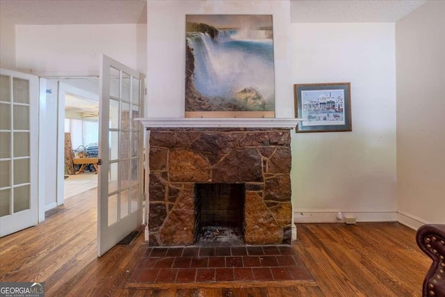 details featuring french doors, hardwood / wood-style floors, a textured ceiling, and a stone fireplace