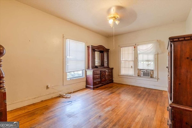 unfurnished bedroom featuring wood-type flooring, cooling unit, and ceiling fan