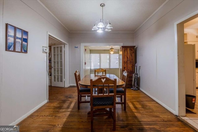 dining room with a textured ceiling, ornamental molding, dark hardwood / wood-style floors, and a notable chandelier