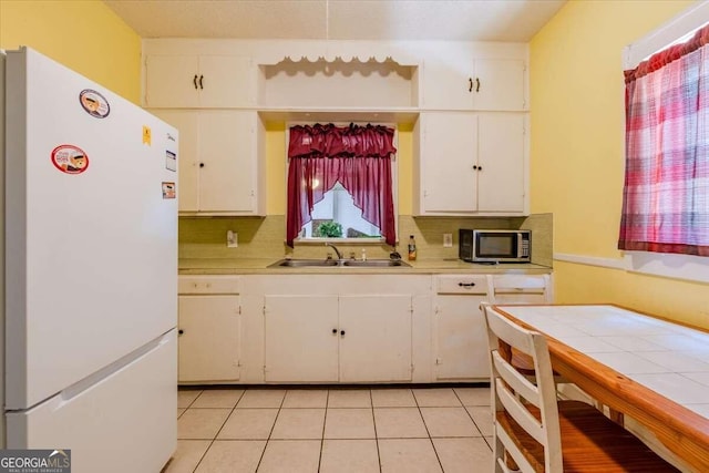 kitchen featuring white cabinets, sink, white fridge, light tile patterned flooring, and decorative backsplash