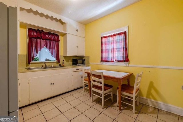 dining space featuring sink and light tile patterned flooring