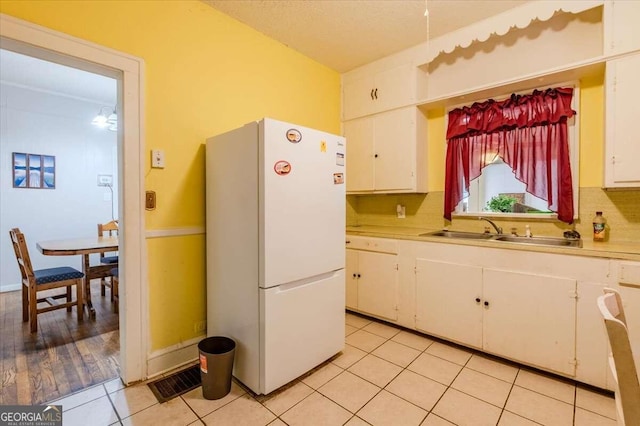 kitchen featuring white refrigerator, light hardwood / wood-style floors, sink, and white cabinets