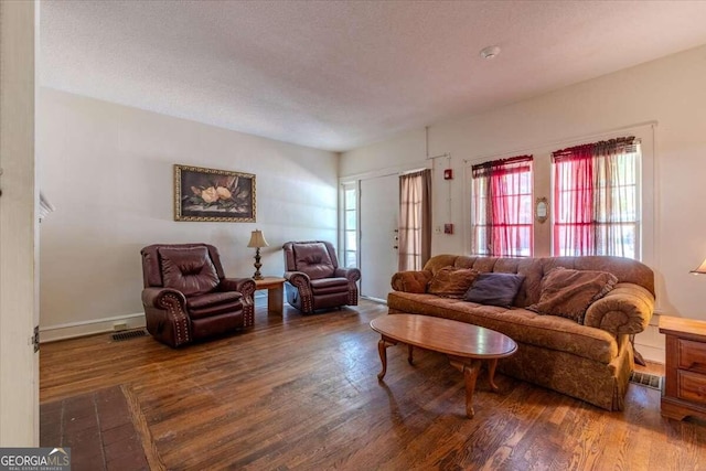 living room featuring dark wood-type flooring and a textured ceiling