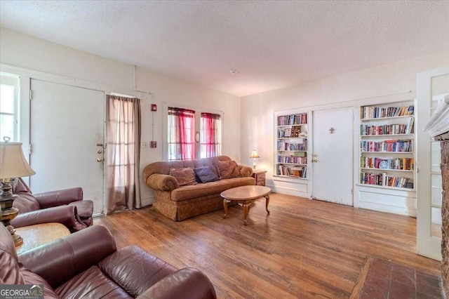 living room featuring wood-type flooring, a textured ceiling, and a healthy amount of sunlight