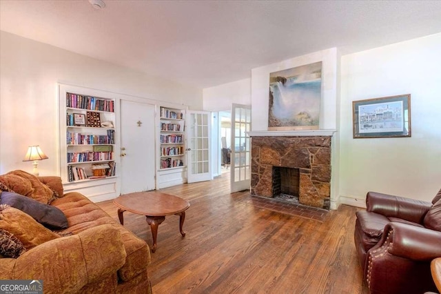 living room with built in shelves, hardwood / wood-style flooring, a fireplace, and french doors